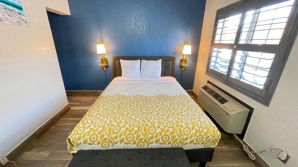 A hotel room with a bed, window, and lamps